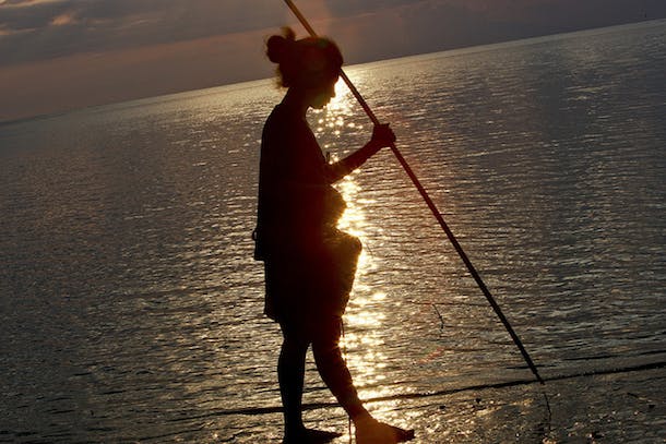Woman Collecting Fish at Sunset
