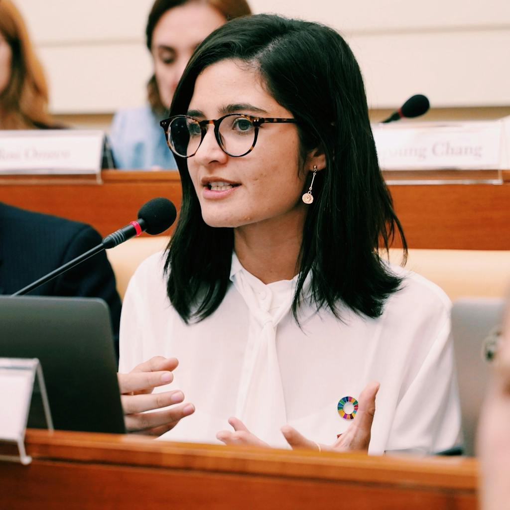 Young Spanish activist speaking against human trafficking while wearing a pin for the Sustainable Development Goals. 