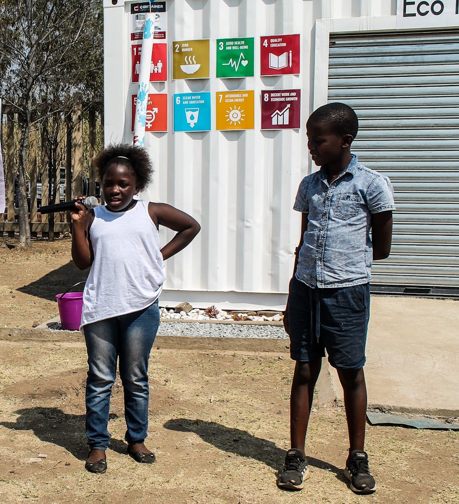 Two South African children speak at an event in front of the Sustainable Development Goals.