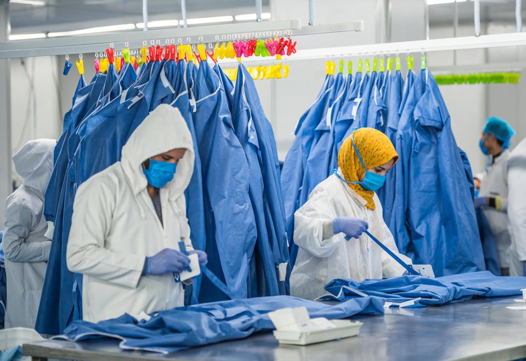 Health workers wearing masks and gloves prepare personal protective equipment