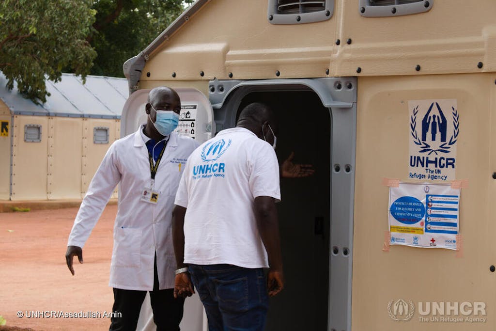 Two men wearing masks outside a UNHCR facility in South Sudan.