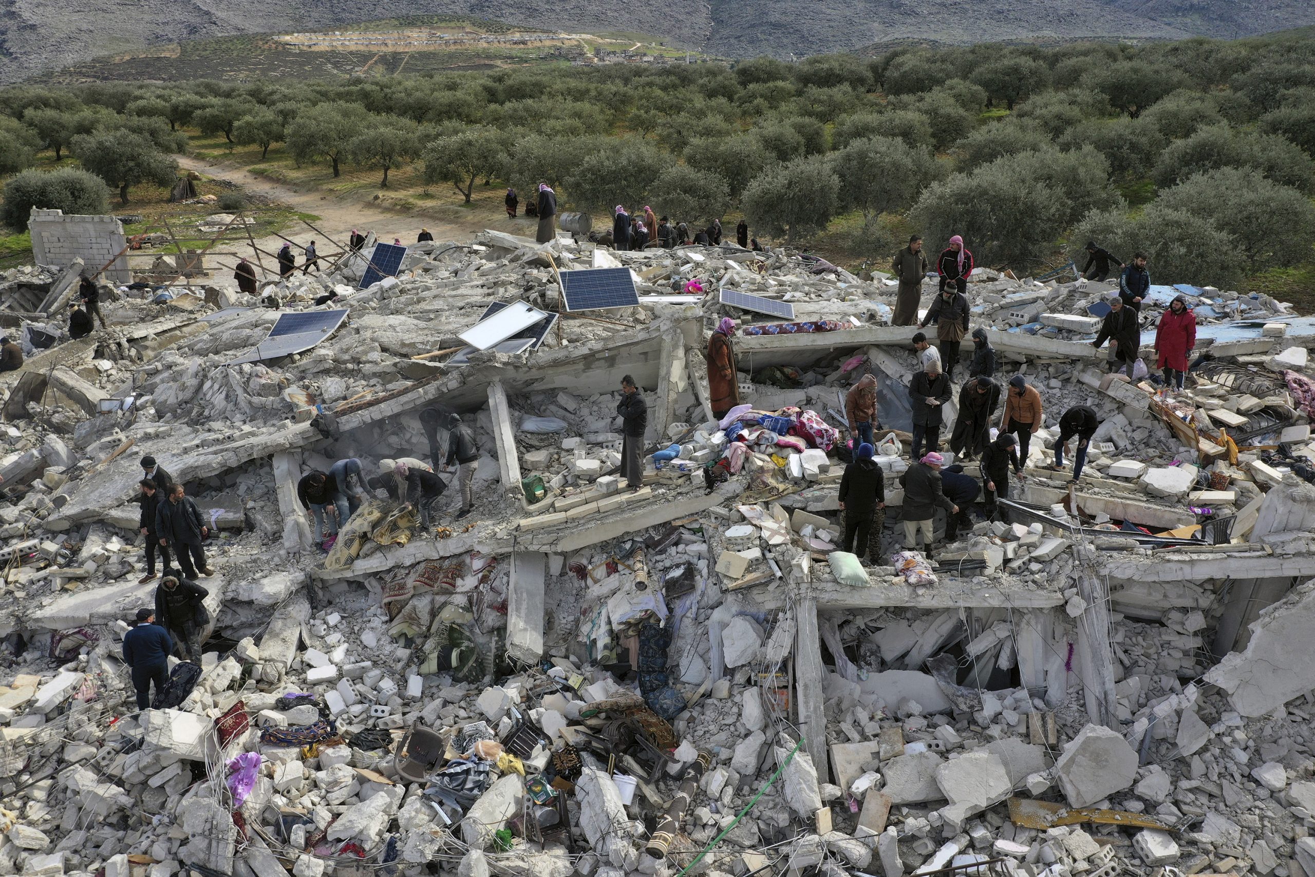 Workers and residents search through the rubble of collapsed buildings in Syria near the Turkish border, in the aftermath of the Turkey-Syria earthquakes.