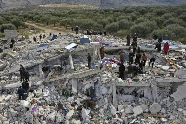 Workers and residents search through the rubble of collapsed buildings in Syria near the Turkish border, in the aftermath of the Turkey-Syria earthquakes.